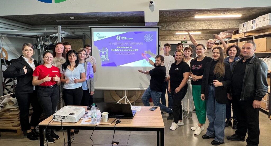 Group of trainees and trainers posing beside a projector during a 3D printing workshop