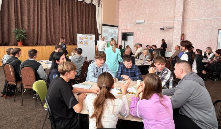 Menschen in einem Seminarraum diskutieren in Gruppen an Tischen.