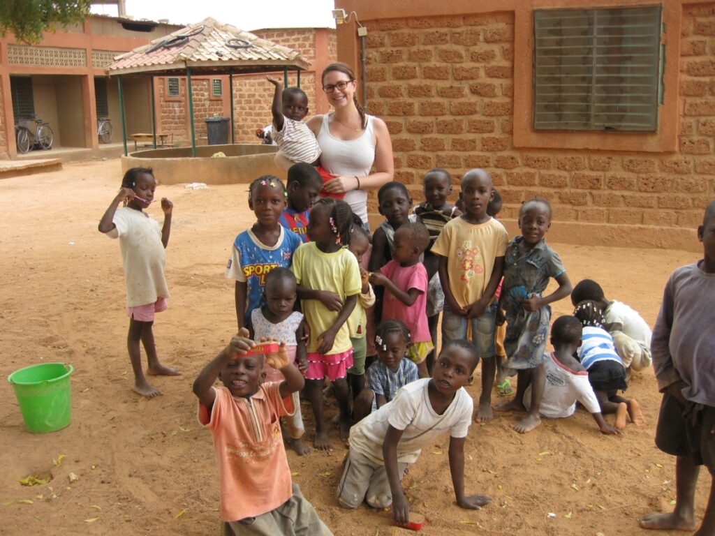 LED staff member stands with a group of children in a rural school courtyard