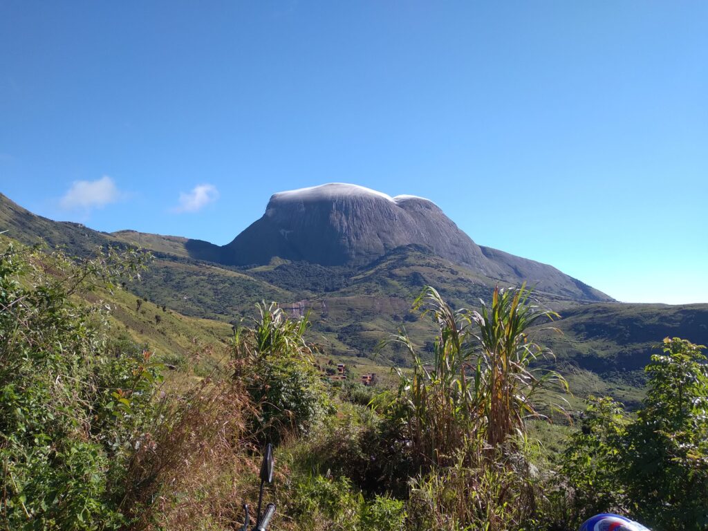 Green mountain landscape with a rounded rocky peak under a clear blue sky