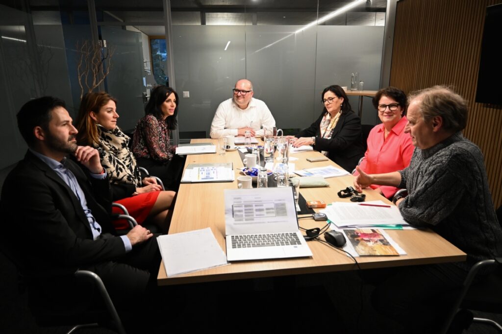 LED team and partners in a formal meeting around a conference table with laptops and documents