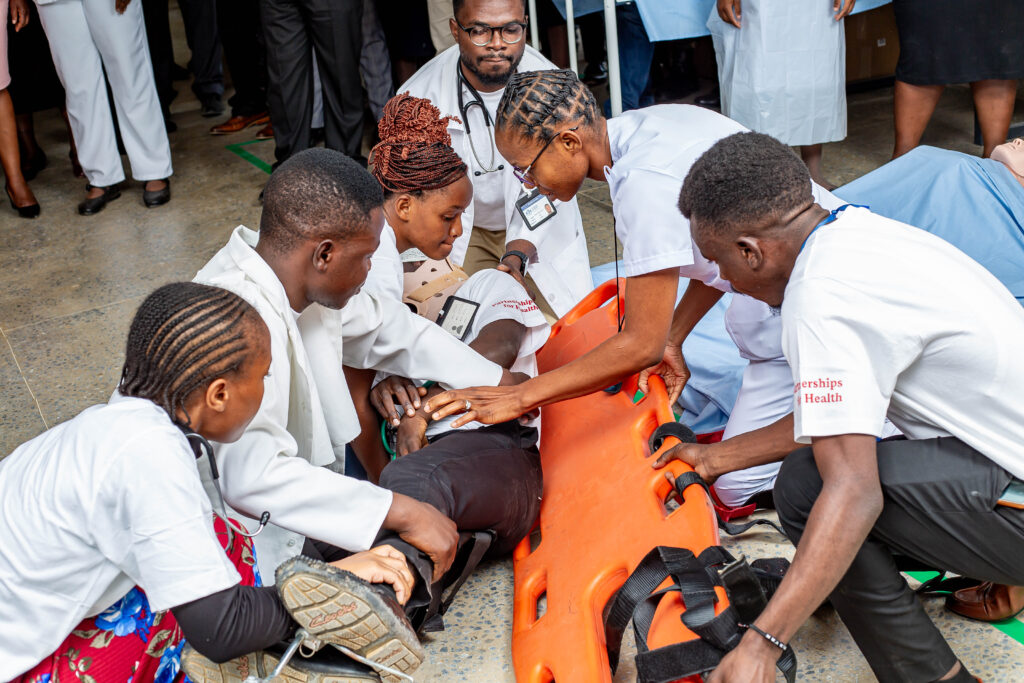 6 junge Menschen, die üben, eine verletzte Person auf eine Trage zu hieven