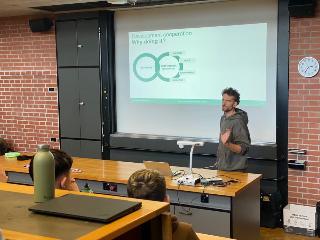 Presenter explains development cooperation slide to students in a classroom