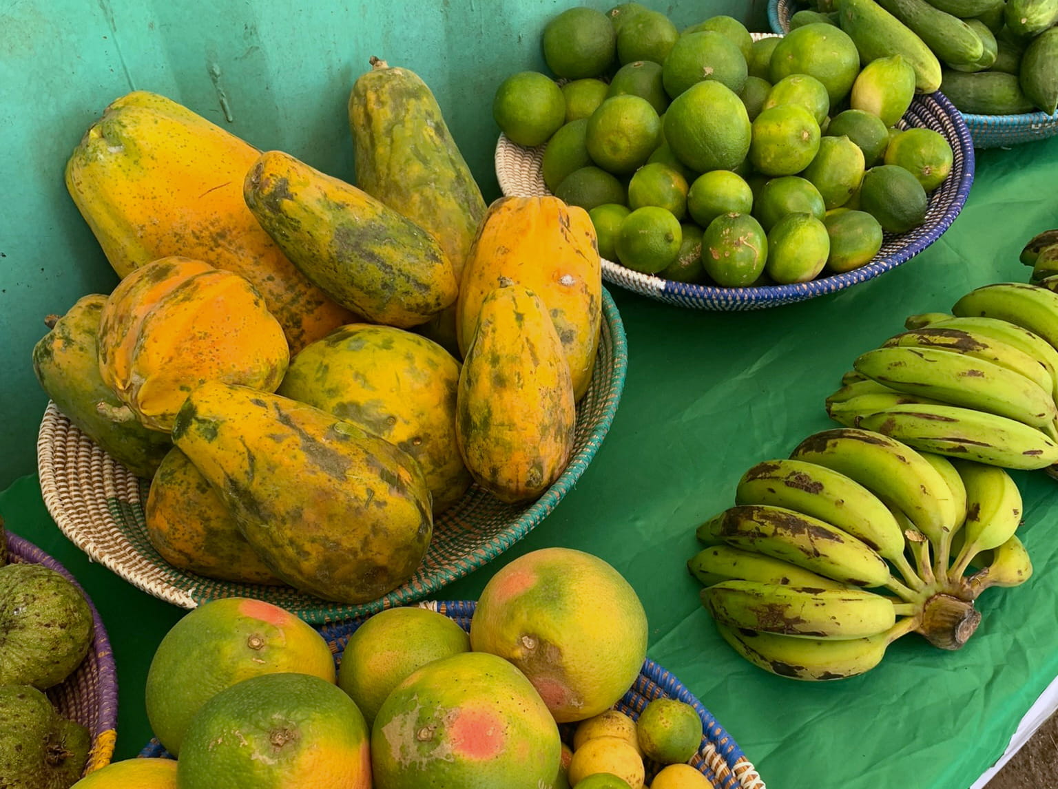 Baskets of papayas, limes and bananas on a green table