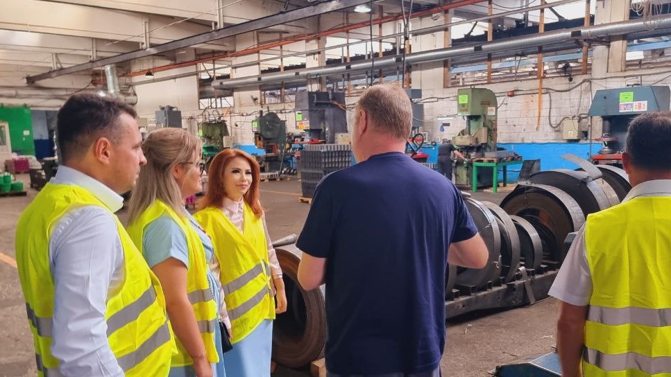 Group of people in safety vests in a factory hall