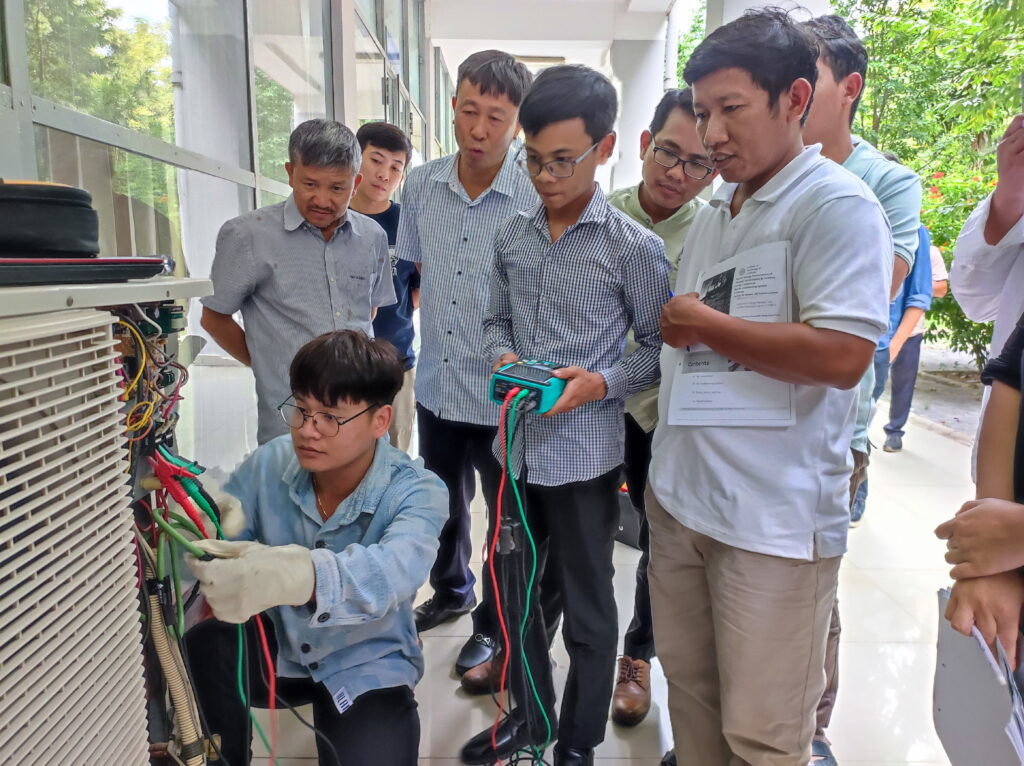 Group of men inspecting electrical equipment during a technical training session outdoors