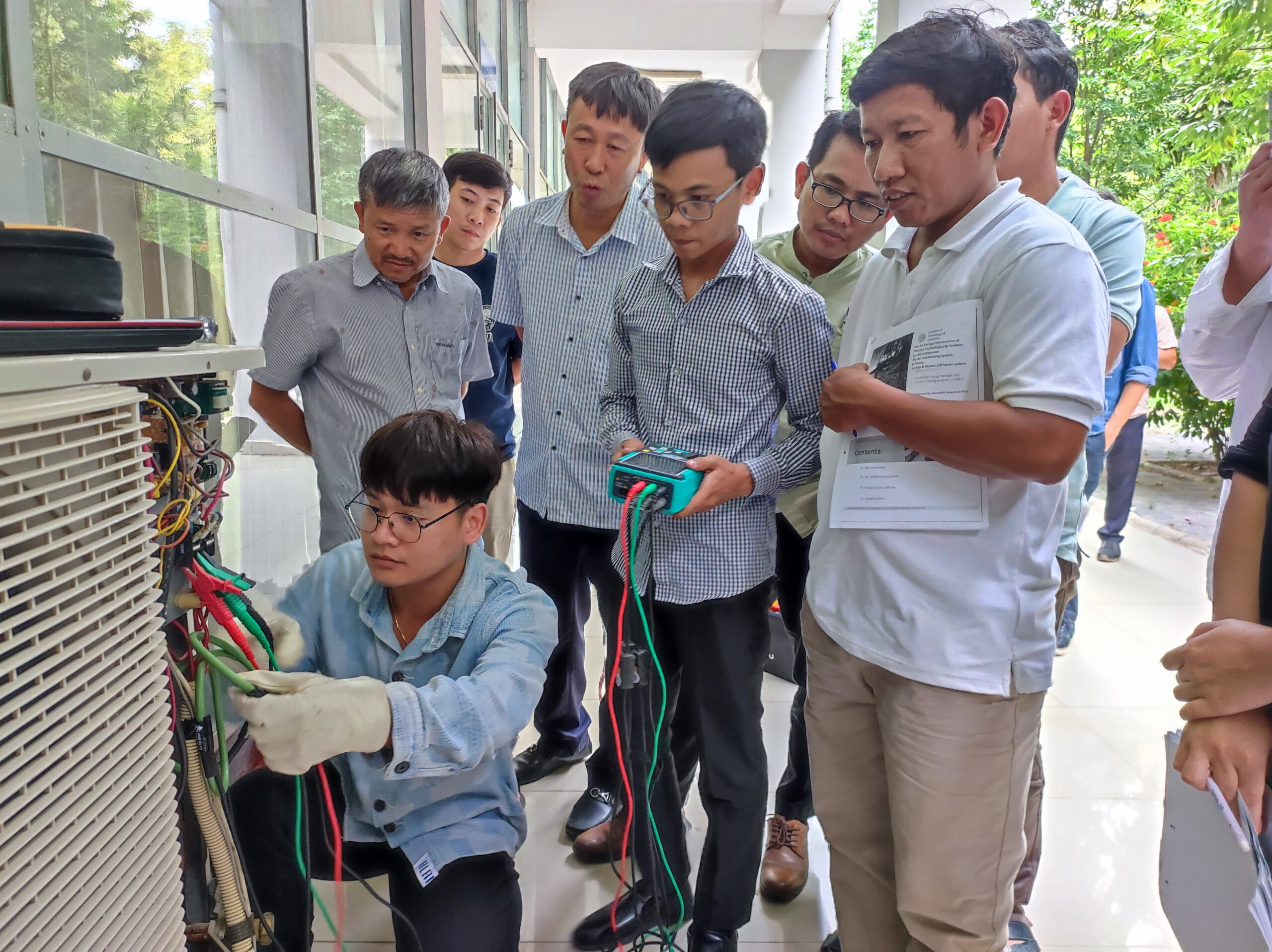 Group of men inspecting electrical equipment during a technical training session outdoors