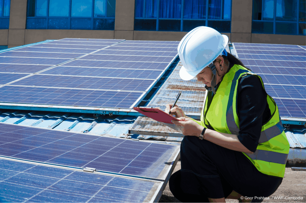 Engineer with helmet and vest checks solar panels on roof