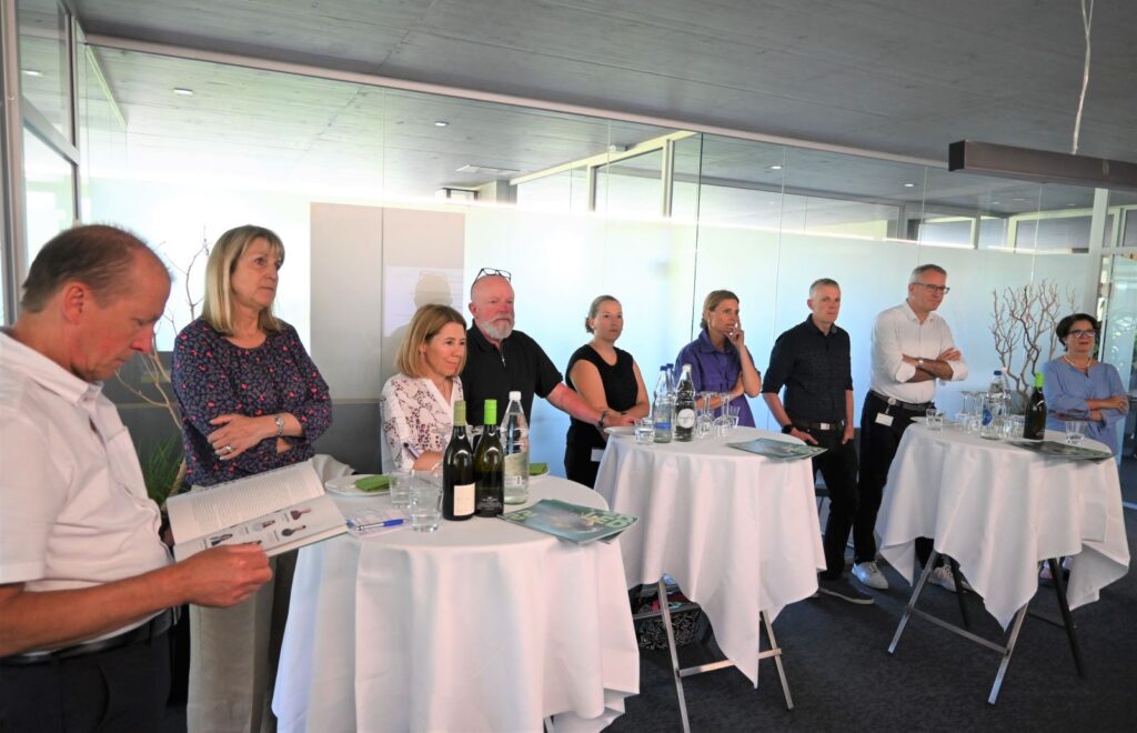 Professionals standing around cocktail tables at a formal LED networking event in a modern conference room