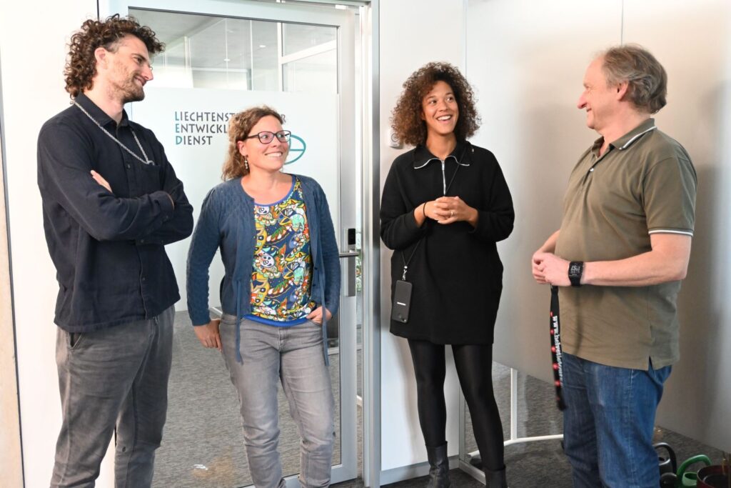 Four colleagues converse in an office hallway at Liechtensteinischer Entwicklungsdienst
