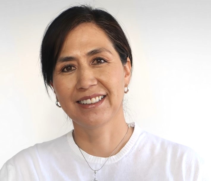 Smiling woman with dark hair against a light background