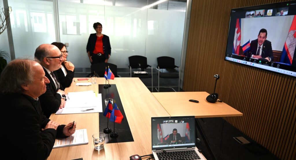 LED representatives in a conference room join a video meeting with an official speaker on screen