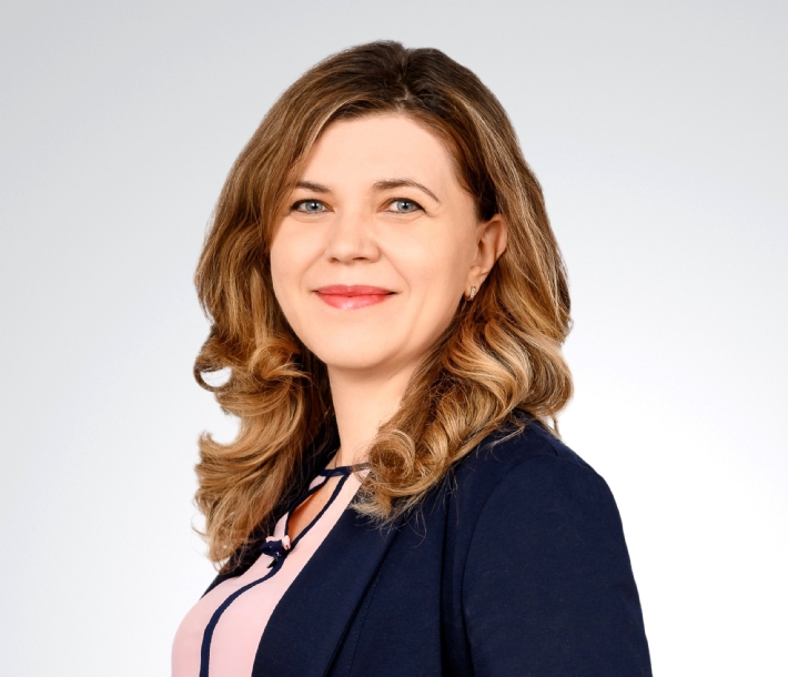 Portrait of a smiling woman in a business outfit against a light background