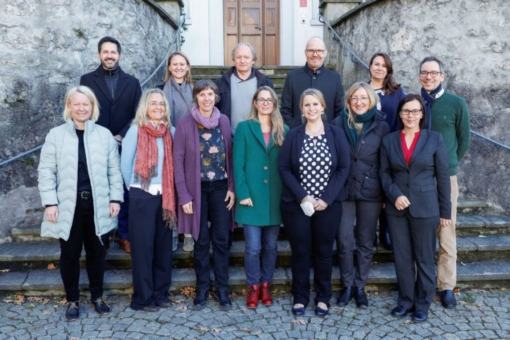 LED team posing on stone steps outside a historic building, wearing winter coats