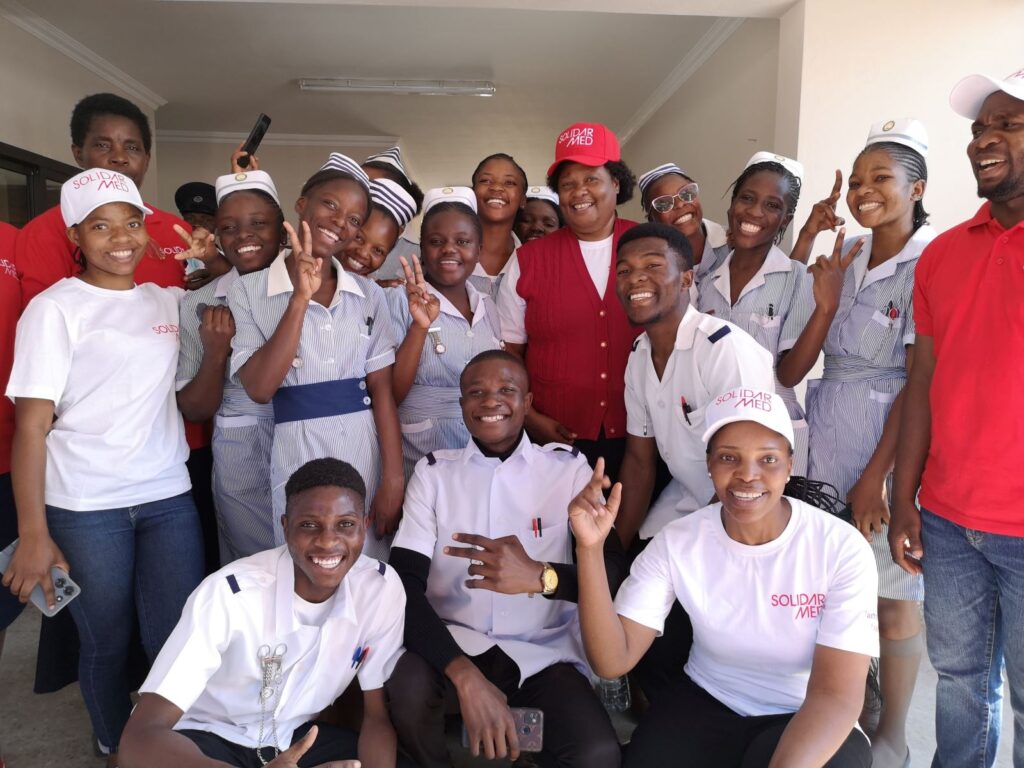 Smiling SolidarMed staff and trainees pose together in uniforms during a group photo
