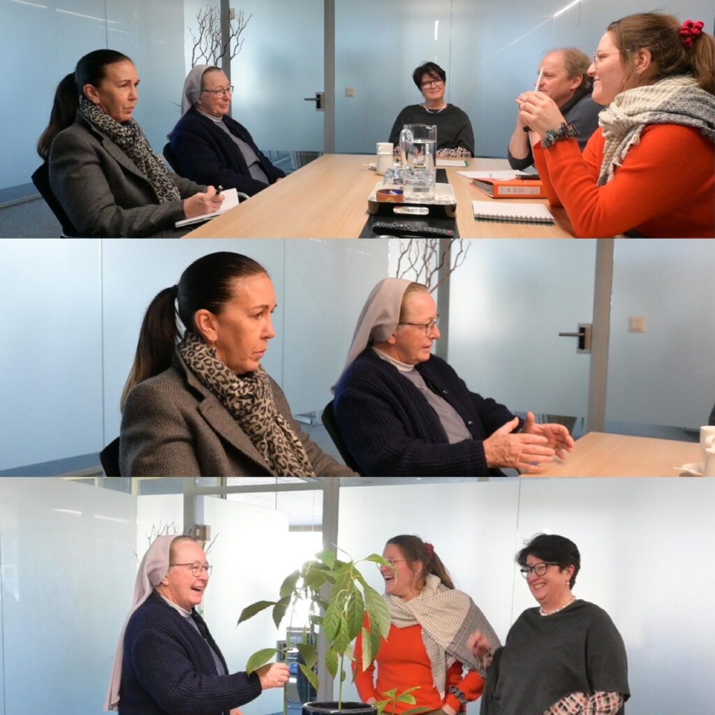 Women and a nun in a meeting room discussing around a conference table