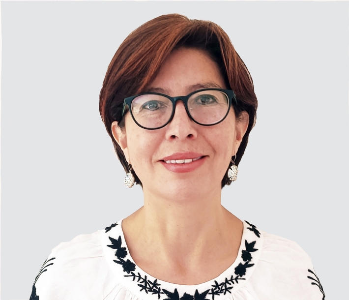 Frau mit Brille und Ohrringen vor neutralem Hintergrund