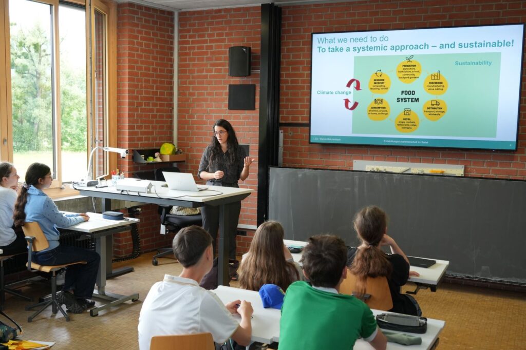 LED presenter explains sustainable food systems to students in a classroom