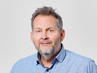 Porträt eines grauhaarigen Mannes in blauem Hemd vor hellem Hintergrund