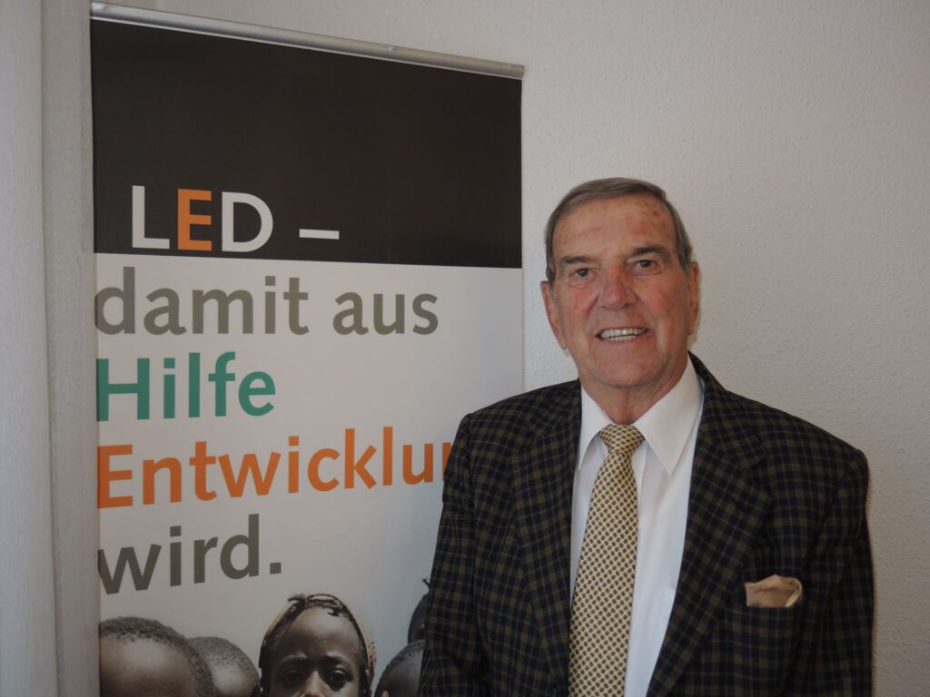LED banner beside a suited man, promoting development aid in German