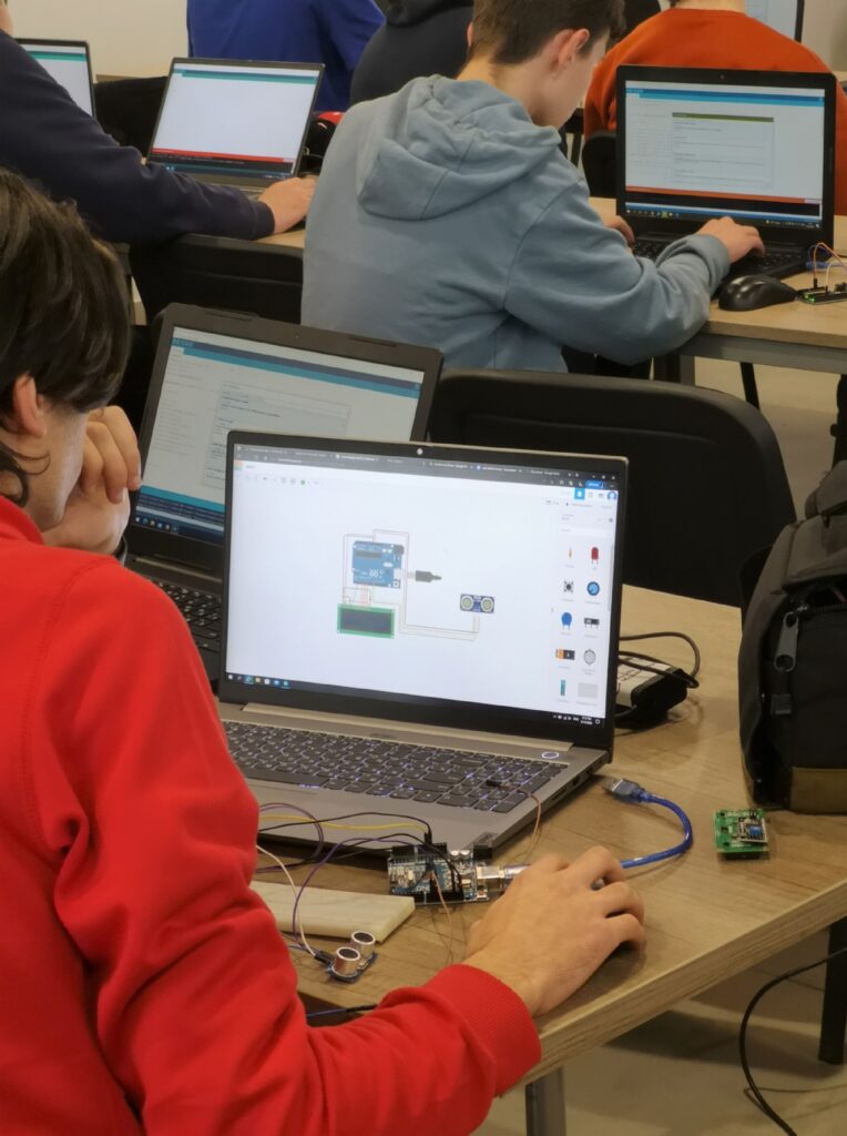 Students program Arduino circuits on laptops during a hands-on technology workshop