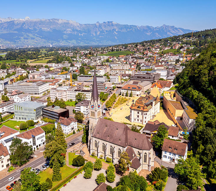 Luftaufnahme von Vaduz mit Kirche, Schloss und Alpenpanorama