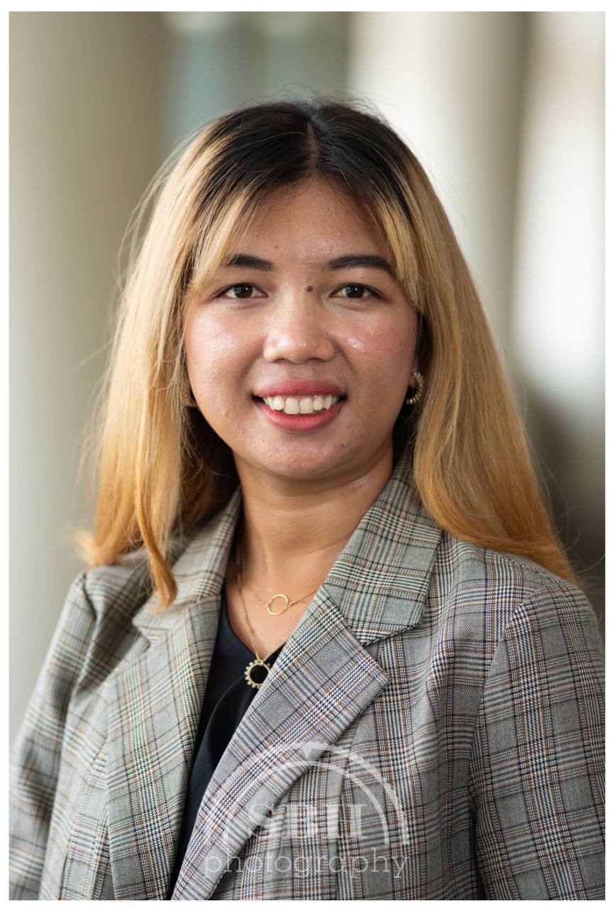 Junge Frau mit hellgrauem Blazer, lächelt in die Kamera