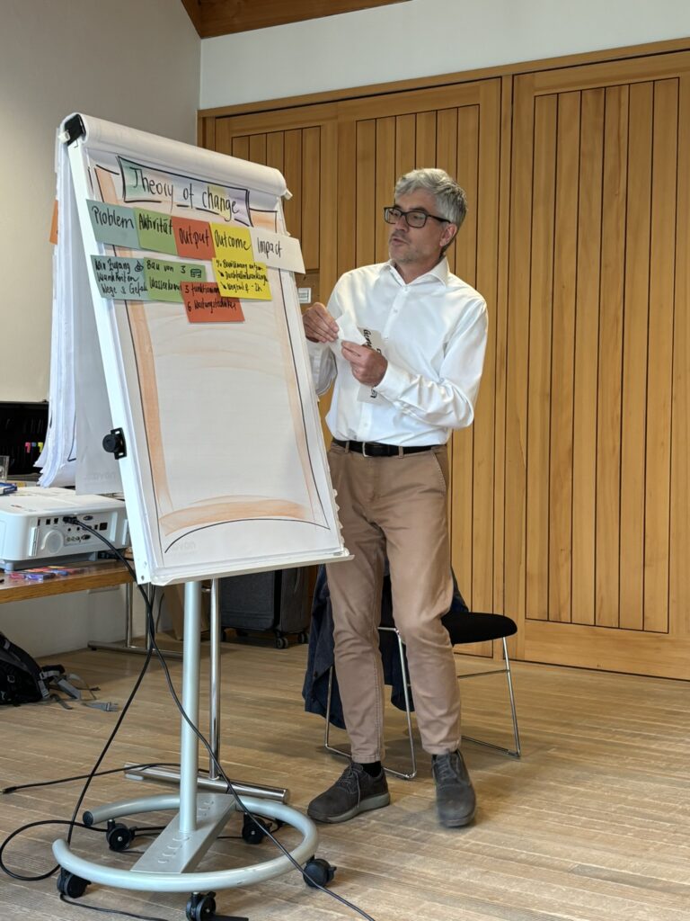 Grauhaariger Mann präsentiert an einem Flipchart
