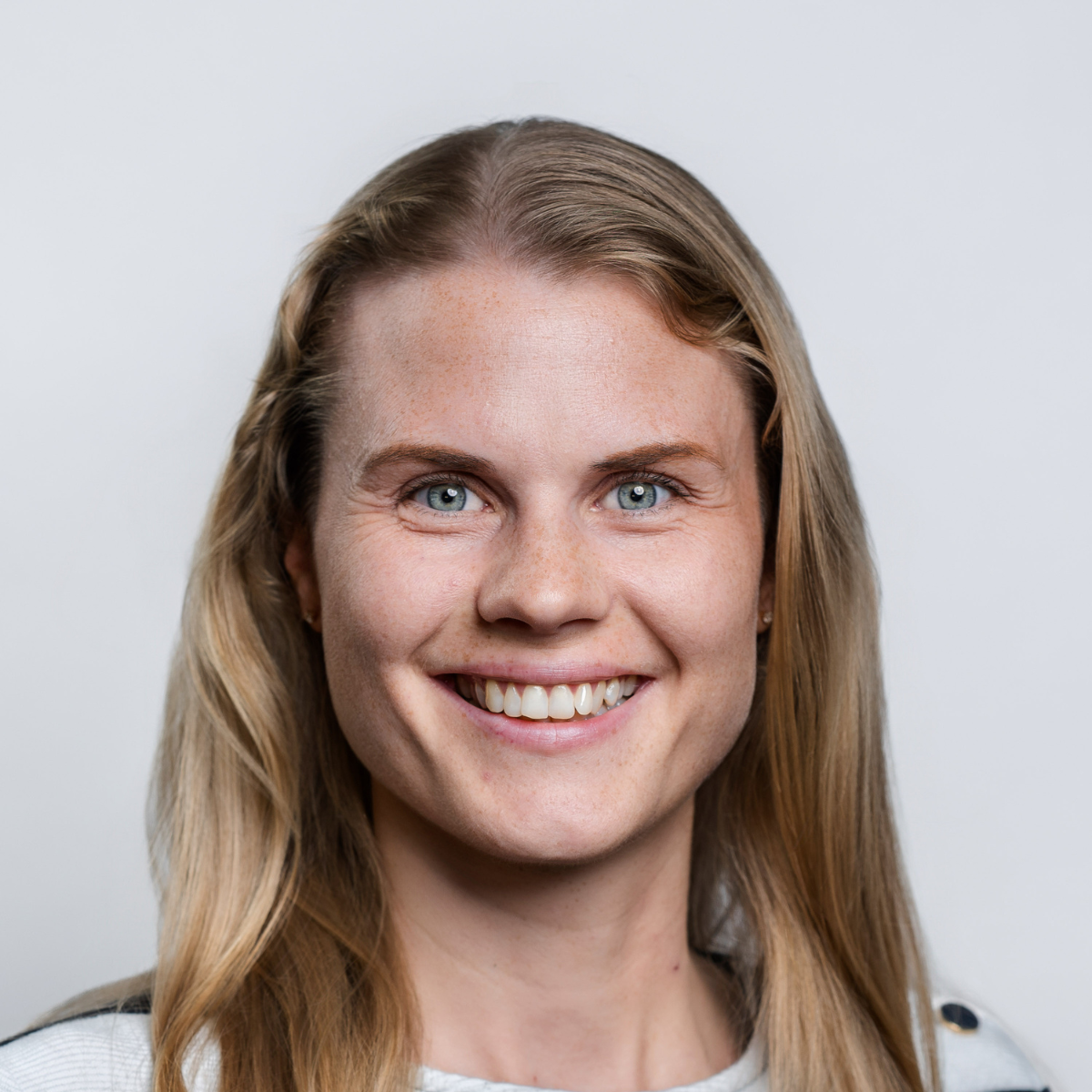 Portraitbild einer lächelnden Frau vor hellem Hintergrund
