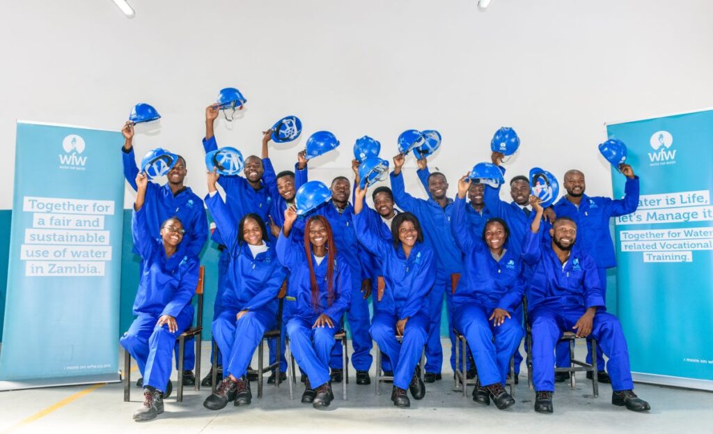 Gruppe von Absolventinnen, die ihre Helme schwenken, in blauen Anzügen
