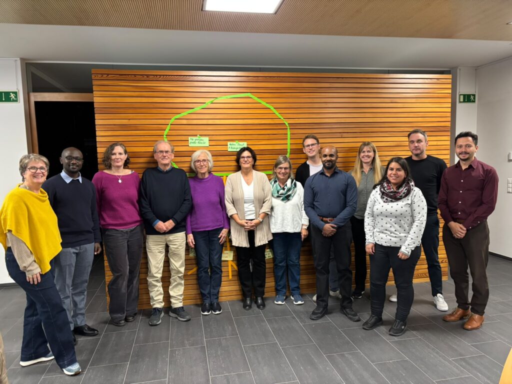 Gruppenfoto der Teilnehmenden des Workshops «Von der Projektidee zur konkreten Umsetzung», gemeinsam organisiert vom Liechtensteinischen Entwicklungsdienst (LED) und dem Netzwerk für Entwicklungszusammenarbeit am 29. Oktober 2026 in Schaan. Die Gruppe steht vor einer holzverkleideten Wand.